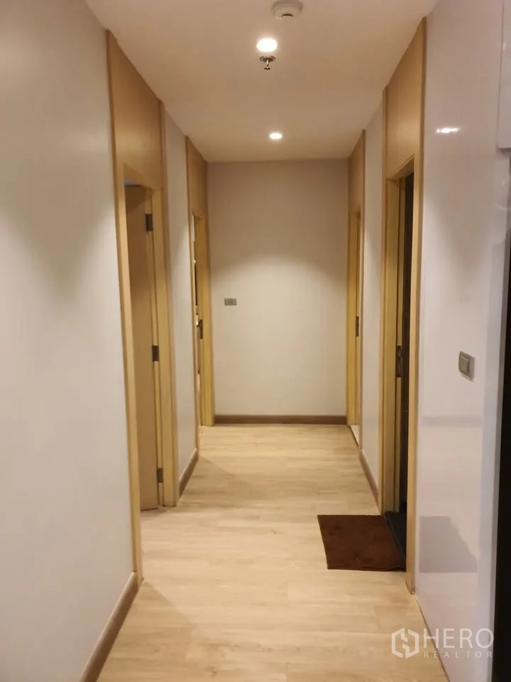 Condominium for rent in Watthana, Bangkok - Bright hallway with light wood flooring leading to bedrooms and bathrooms.
