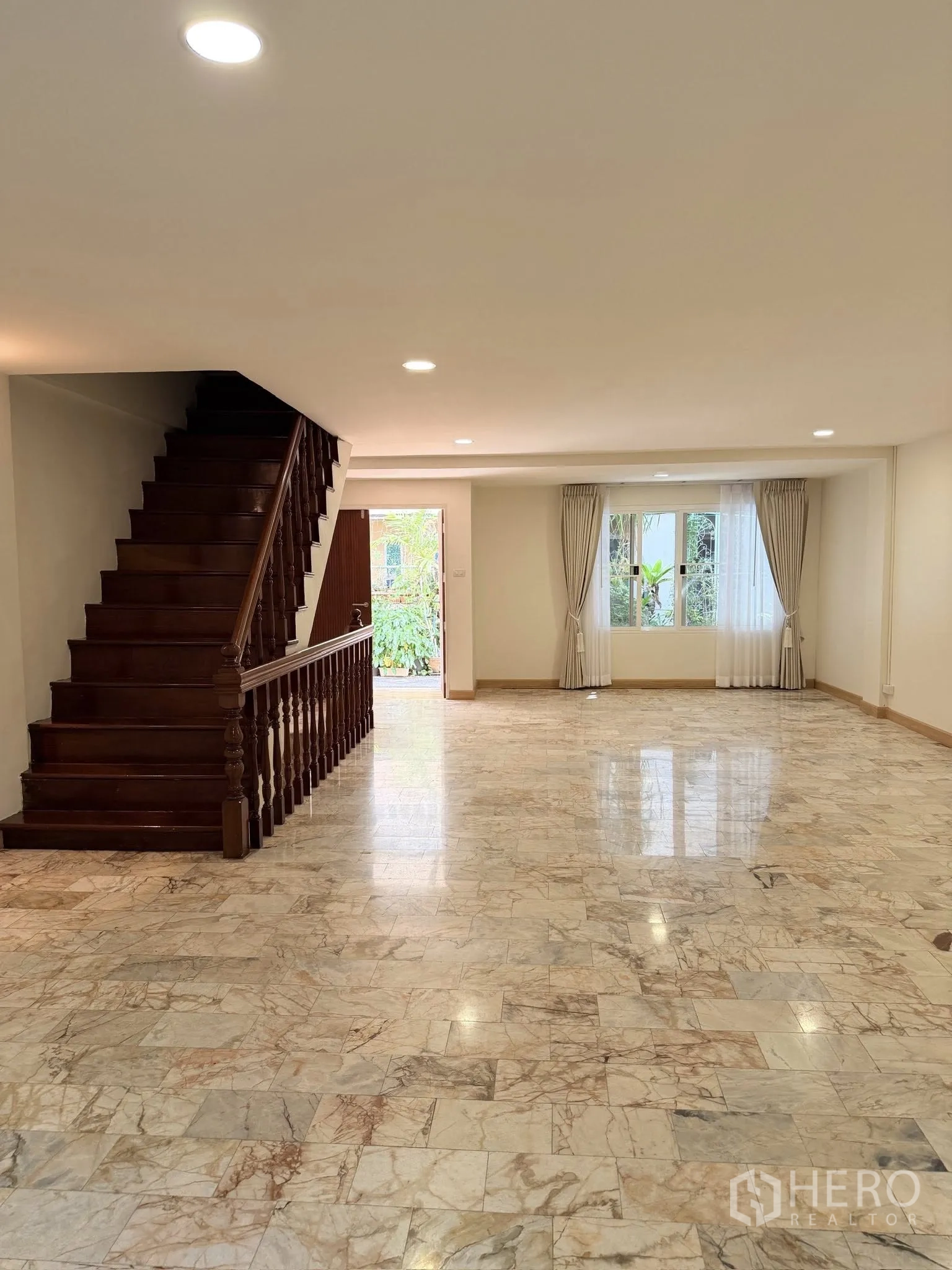 Townhouse for rent or sale in Yan Nawa, Bangkok - Large open-plan living area with wooden staircase and marble floors.