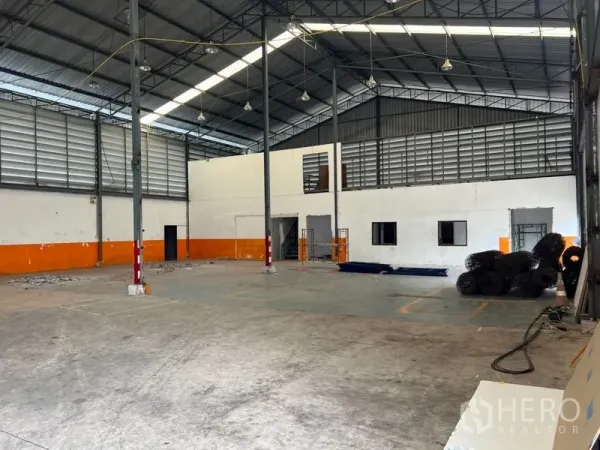 Warehouse for rent in Prawet, Bangkok - Spacious warehouse interior featuring high steel truss roof, skylights and louvered ventilation, concrete floor and built‑in office rooms.