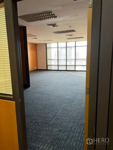 Office Space for rent - Doorway view into a bright office with large panoramic windows and suspended ceiling lights.