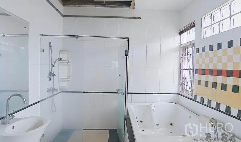 独立式住宅 出售在Bang Kapi, Bangkok - 明亮浴室，玻璃淋浴间、按摩浴缸与瓷砖墙面，带窗采光。