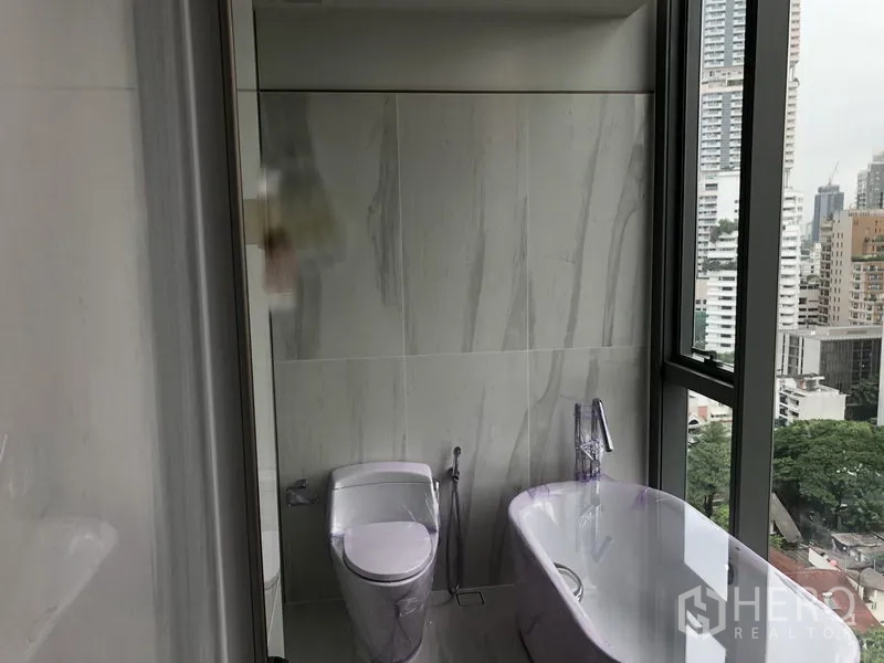 公寓 出租或出售在Khlong Toei, Bangkok - 现代卫浴设独立浴缸与大窗，可观赏城市天际线。