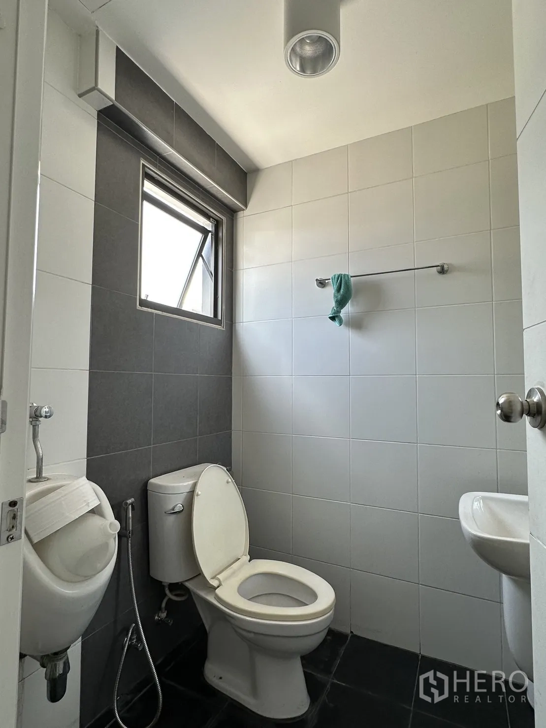 Factory for rent or sale in Pathum Thani - Clean tiled restroom with toilet, urinal and sink.
