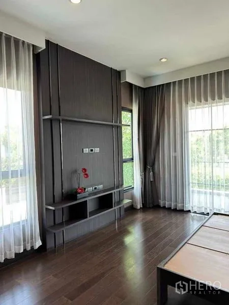 独立式住宅 出售在Prawet, Bangkok - 转角房间，深色木地板，电视背景墙与大窗。