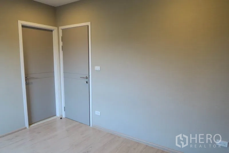 Townhouse for rent in Suan Luang, Bangkok - Bedroom with light wood flooring, two interior doors, and neutral walls.