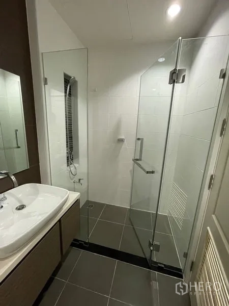 Townhouse for rent in Bang Kapi, Bangkok - Bathroom with wide sink, mirror and clear glass shower enclosure.