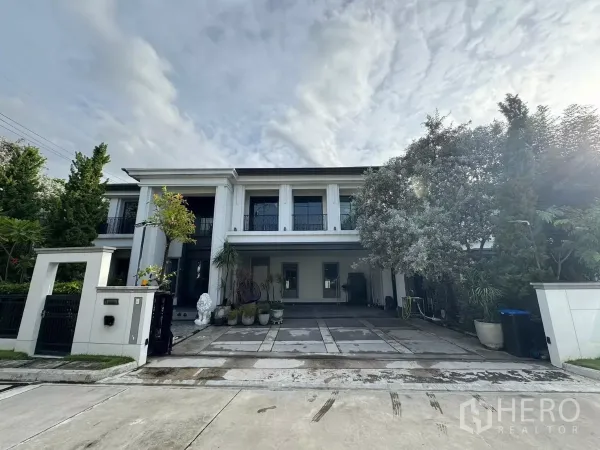 Detached House for sale in Mueang Pathum Thani, Pathum Thani - Two-storey luxury detached house facade with double-height columns, gated driveway and landscaped trees.