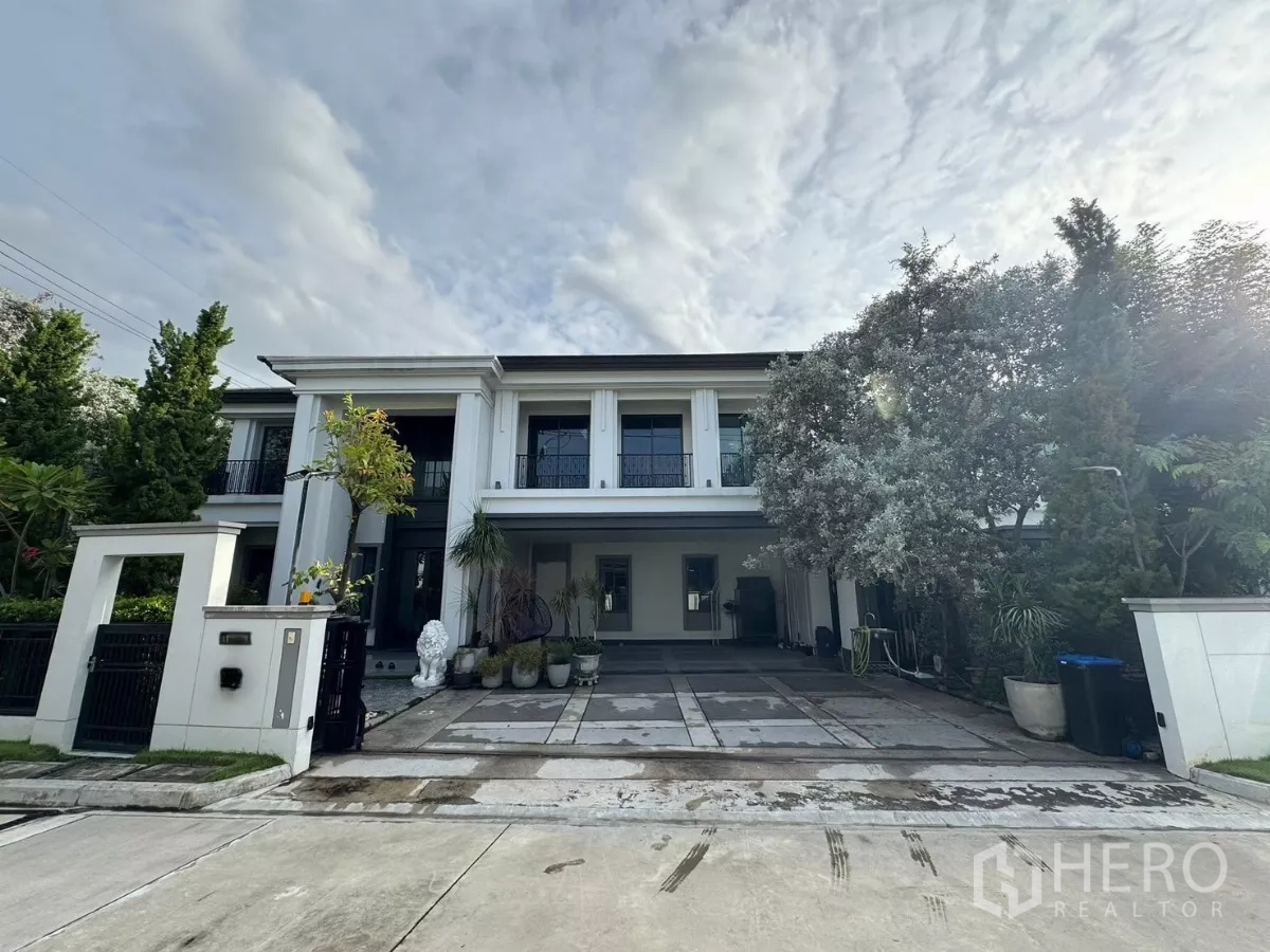 独立式住宅 出售在Mueang Pathum Thani, Pathum Thani - 两层豪华独栋住宅外观，挑高立柱、车道与景观树。