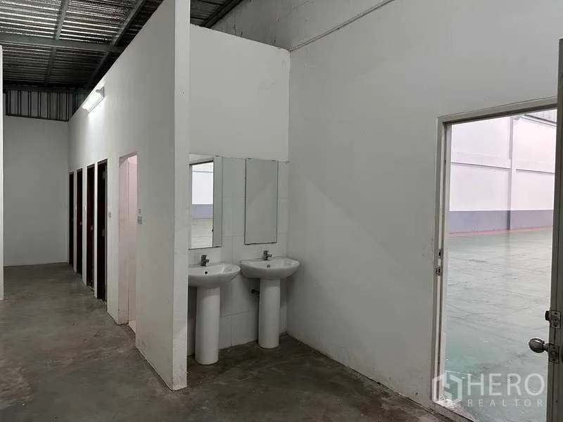工厂 出租或出售在Bang Phli, Samut Prakan - 厂内洗手区与多间卫生间，旁侧为通往仓库的门。