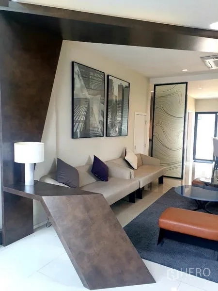 Home Office for rent in Bang Phli, Samut Prakan - Stylish sitting area with sofa, geometric feature wall and glass door.