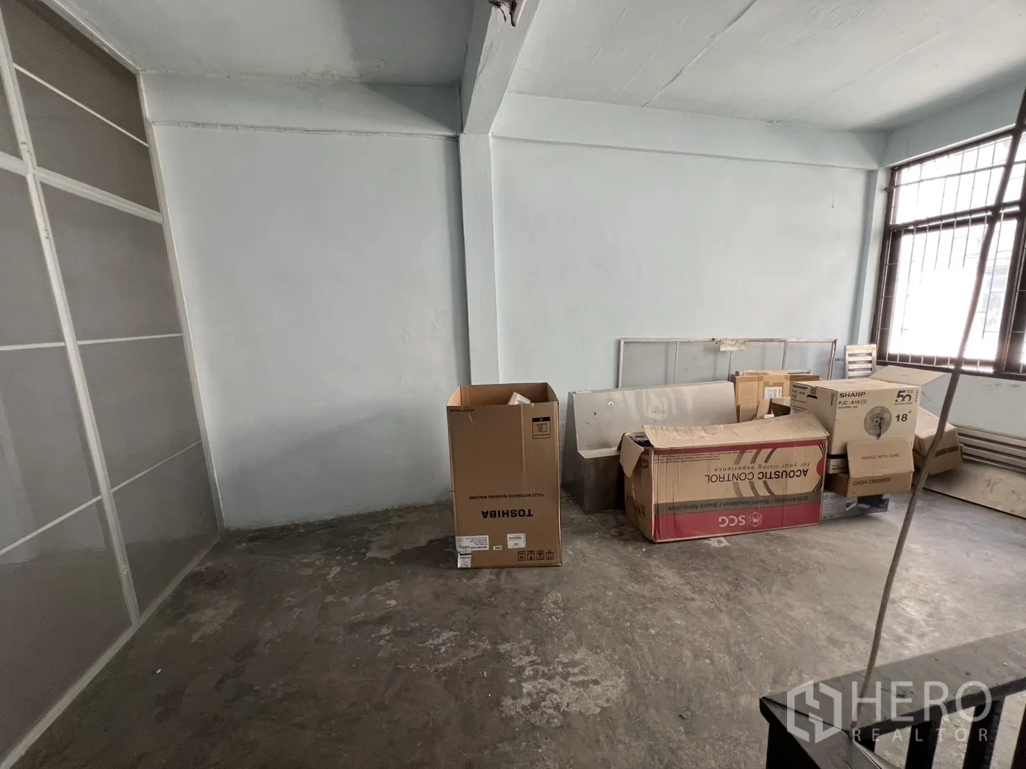 店屋 出租或出售 - 半装修房间，水泥地面，堆放纸箱，带护栏窗。