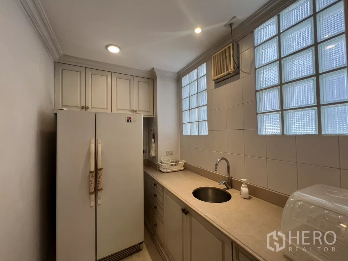Townhouse for sale in Watthana, Bangkok - Compact kitchen with stone countertop, double-door fridge and glass-block windows.