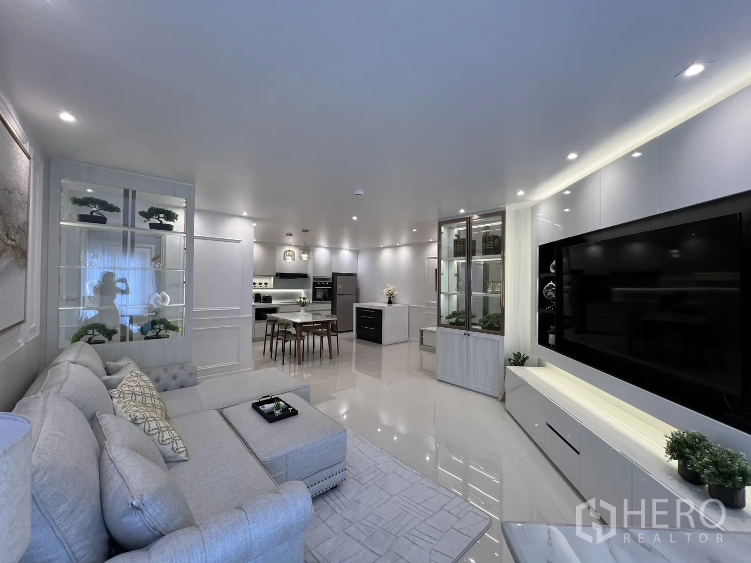 Condominium for rent in Yan Nawa, Bangkok - Open-plan lounge and kitchen with display cabinets, dining set, and recessed lighting.