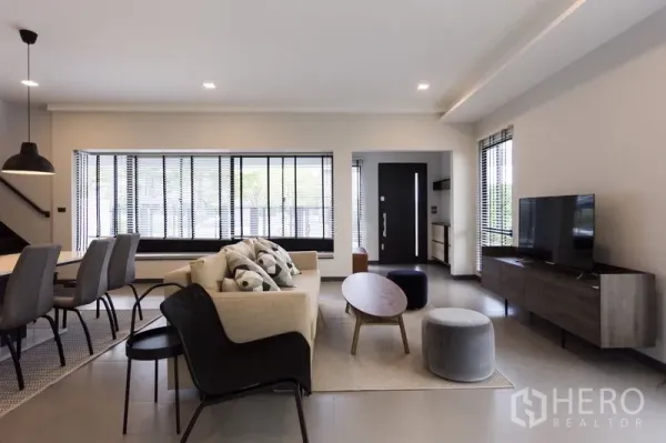 Townhouse for rent in Samut Prakan - Cozy living room with sofa set, TV console and large windows with blinds.