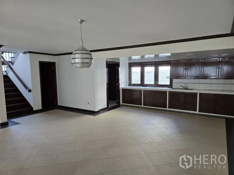 独立式住宅 出租在Watthana, Bangkok - 开放式客餐厅，沿墙设置长排厨房柜与窗户。
