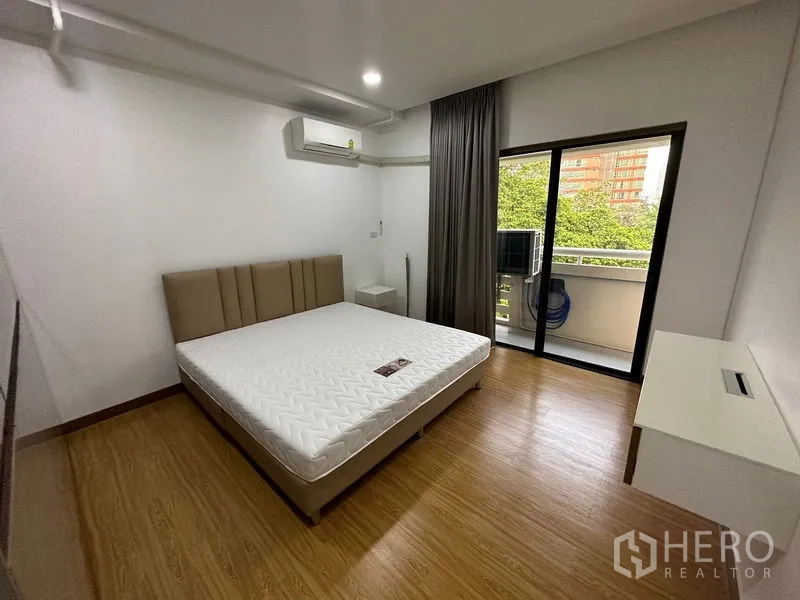 Condominium for rent in Watthana, Bangkok - Primary bedroom with sliding door to balcony and abundant natural light.