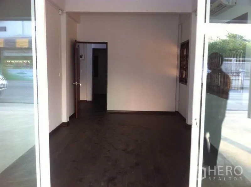 Warehouse for rent in Lam Luk Ka, Pathum Thani - Ground-floor office or showroom with a glass entrance and dark wood flooring.