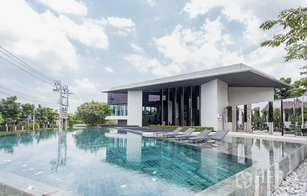 Detached House for rent in Bang Kapi, Bangkok - Estate clubhouse featuring a large outdoor swimming pool with sun loungers.