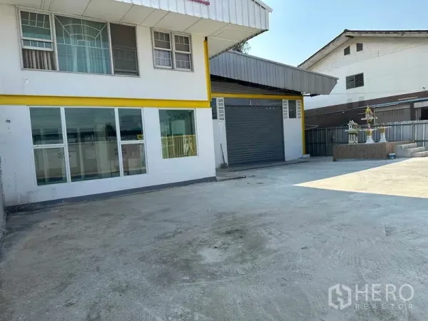 Warehouse for rent in Nakhon Pathom - Exterior view of the warehouse and office frontage with wide concrete yard for truck parking and maneuvering.