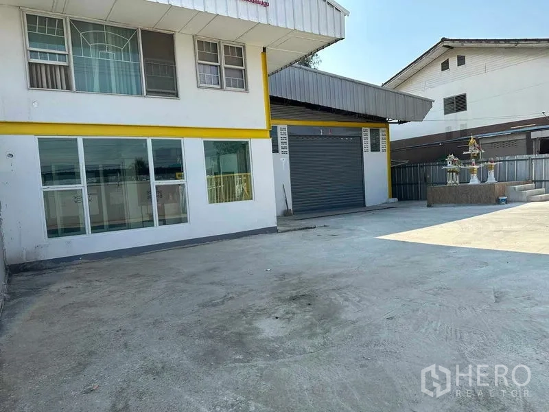 Warehouse for rent in Nakhon Pathom - Exterior view of the warehouse and office frontage with wide concrete yard for truck parking and maneuvering.
