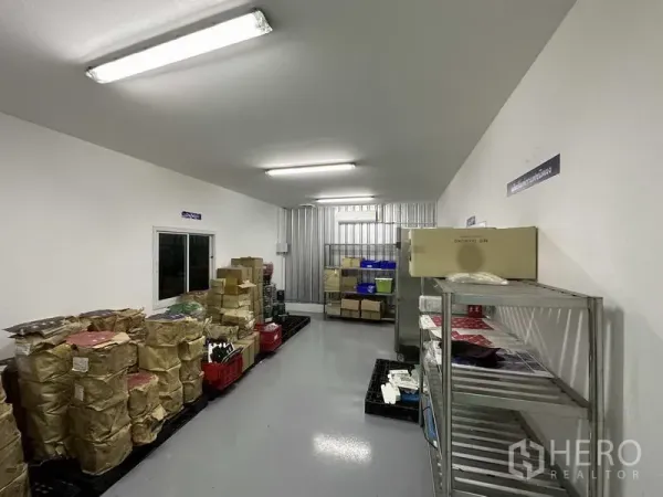 Factory for rent in Khlong Luang, Pathum Thani - Air-conditioned storage room with metal racks, sealed packages and grey epoxy flooring.