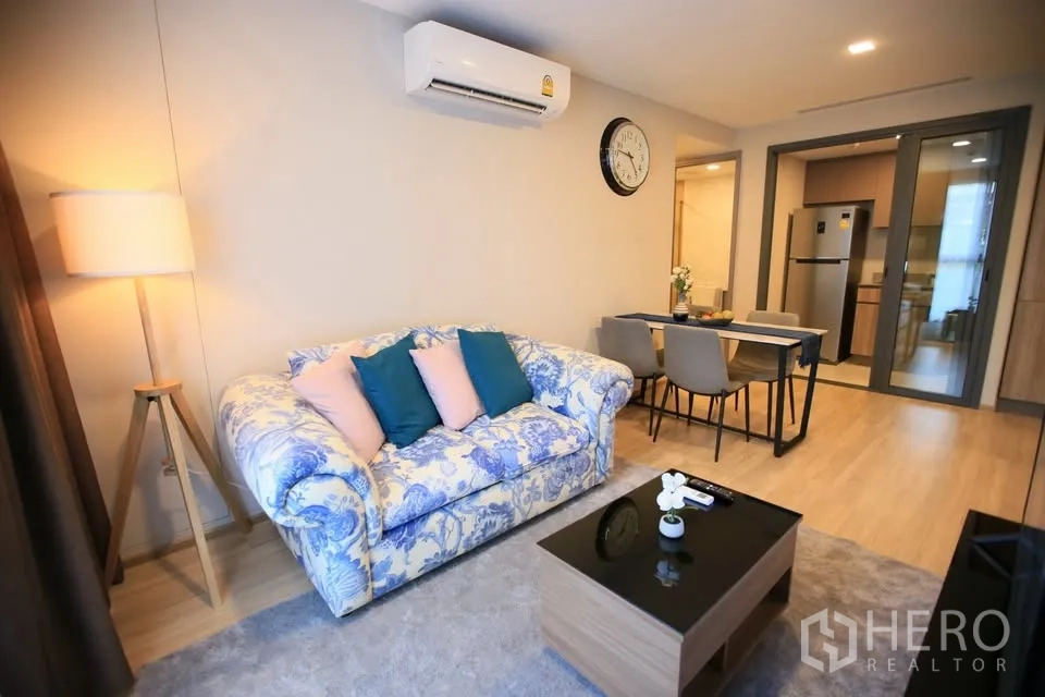 公寓 出租在Watthana, Bangkok - 温馨客厅，花纹沙发，四人餐桌，滑门后为厨房。