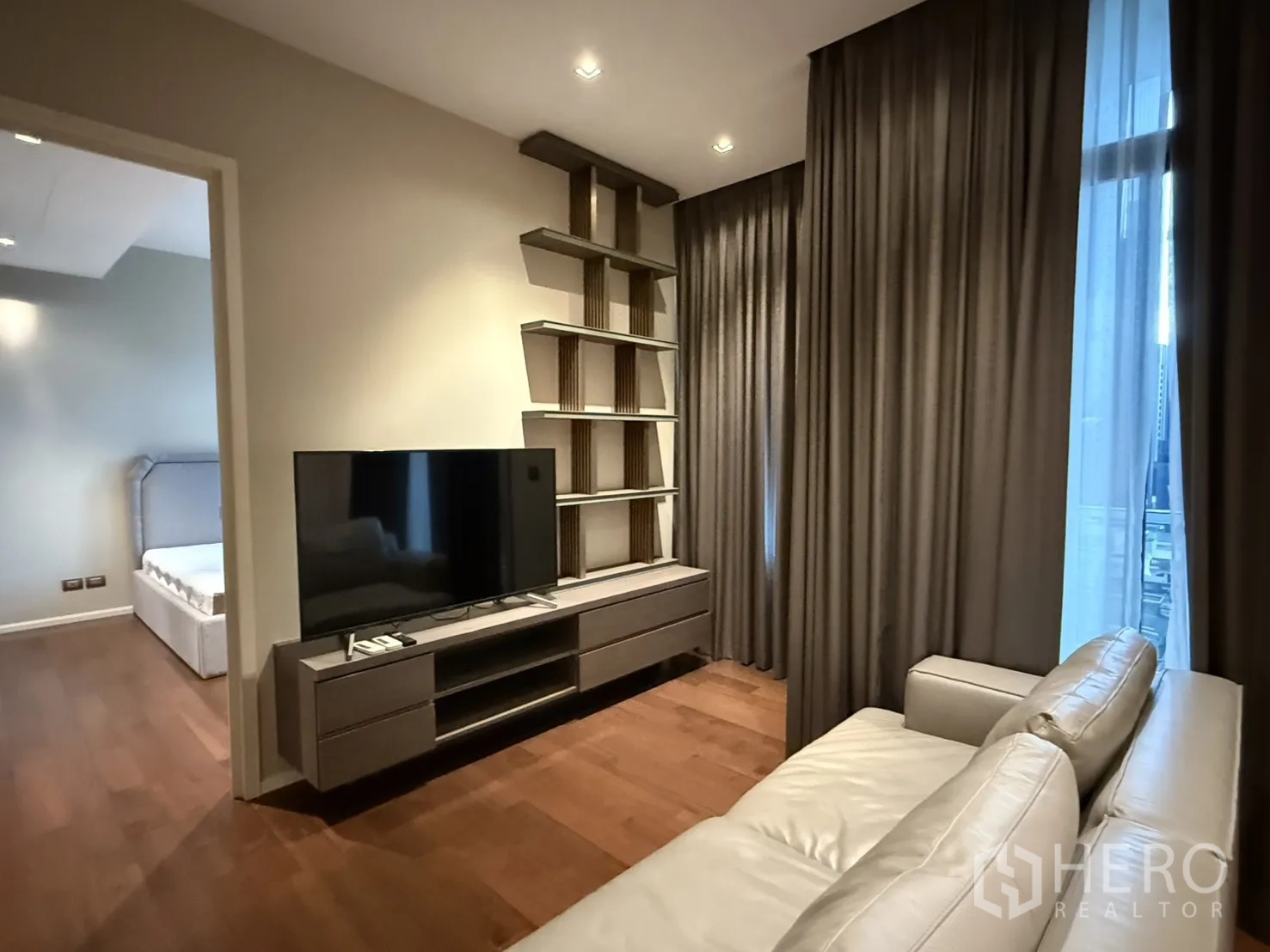 คอนโด for rent in Watthana, Bangkok - ห้องนั่งเล่นสไตล์โมเดิร์น มีโซฟาหนัง ตู้วางทีวี ชั้นวางบิลท์อิน พื้นไม้ ผ้าม่านสูง และมองเห็นทางเข้าห้องนอน