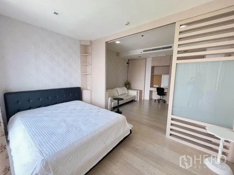 คอนโด ขาย - ห้องนอนหลักกว้าง เปิดเชื่อมพื้นที่ทำงานด้วยฉากกั้นสไลด์ มีชั้นบิวท์อินและโซฟา