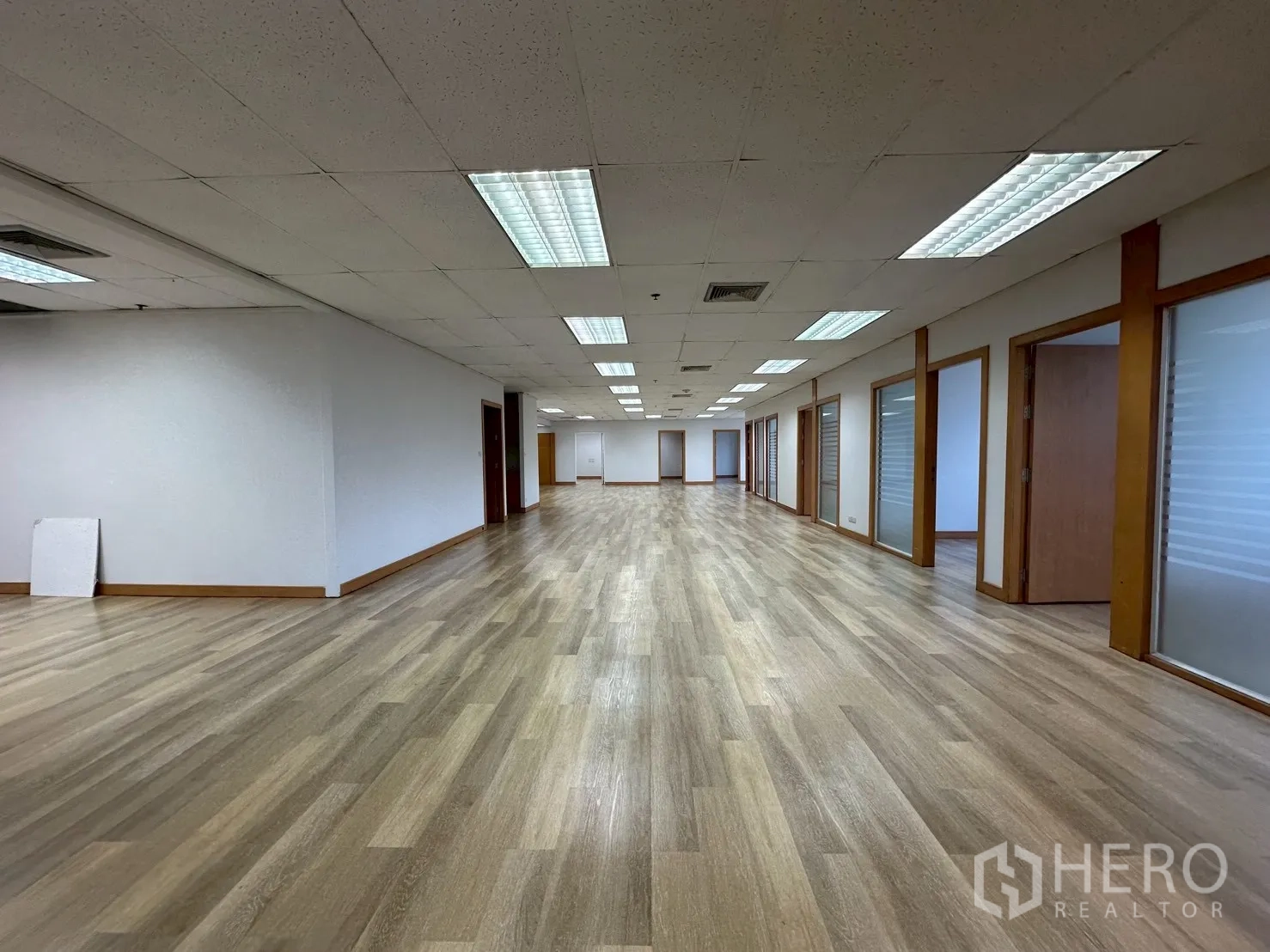 Office Space for rent - Long corridor-style workspace with multiple glass doors and warm wood flooring.