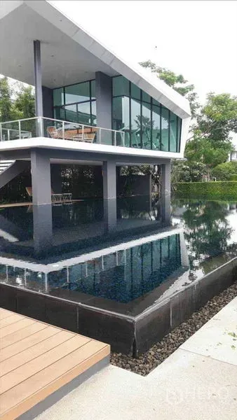 Townhouse for rent - Modern glass-walled clubhouse beside an infinity-edge swimming pool surrounded by greenery.