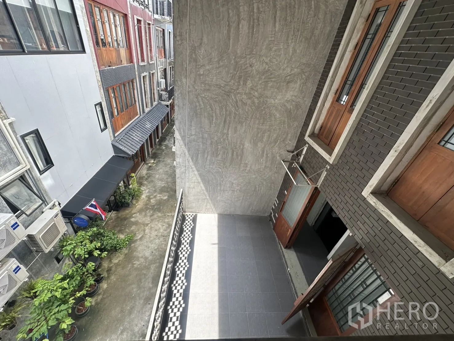 带办公室的家 出租在Pathum Wan, Bangkok - 俯瞰狭窄小巷，可见绿植、泰国国旗与楼体阳台。