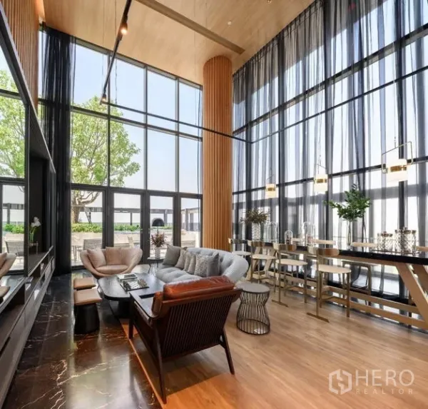 Condominium for rent in Khlong Toei, Bangkok - Double-height residents’ lounge with floor-to-ceiling windows, cozy sofas, and work tables.