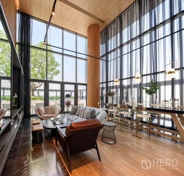 Condominium for rent in Khlong Toei, Bangkok - Double-height residents’ lounge with floor-to-ceiling windows, cozy sofas, and work tables.