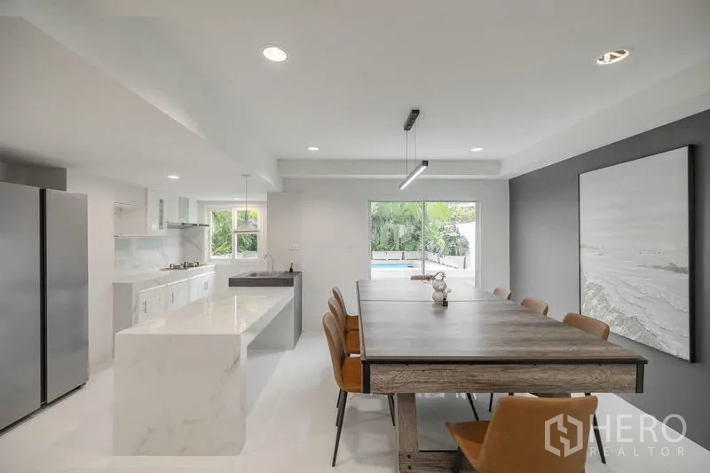 Townhouse for sale - Open-plan kitchen and dining with marble island, long table and pool outlook.