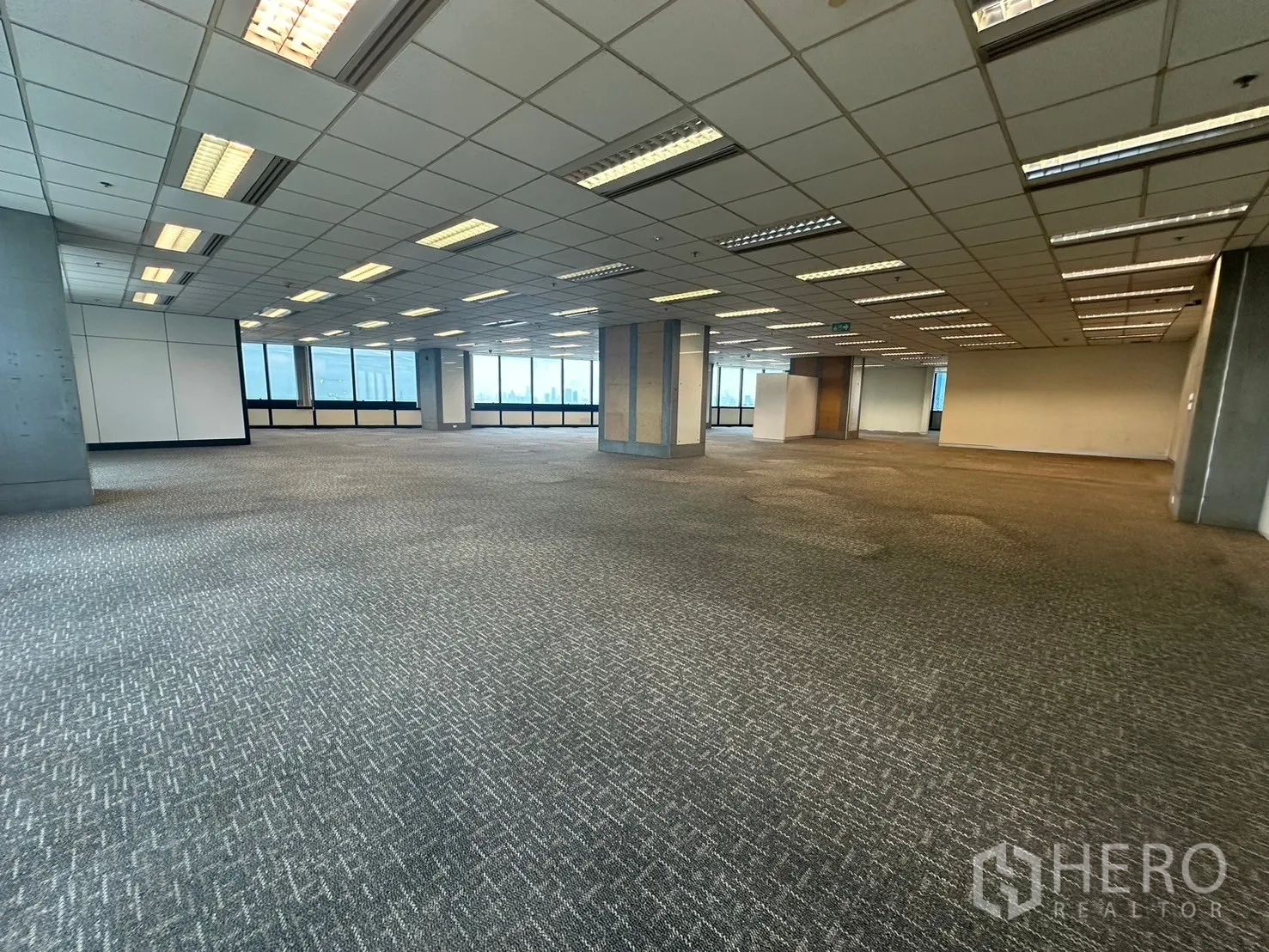 Office Space for rent in Khlong Toei, Bangkok - Expansive carpeted open-plan office with grid ceiling lights and broad city views.