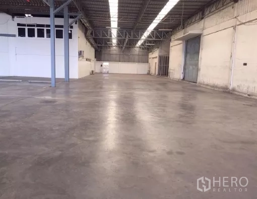 Warehouse for rent in Khlong Luang, Pathum Thani - Open bay with roller shutter door, steel columns and power points along the wall.