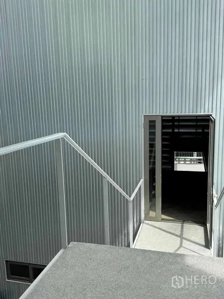 Home Office for rent or sale - Outdoor stair landing leading to a door on a ribbed metal wall.