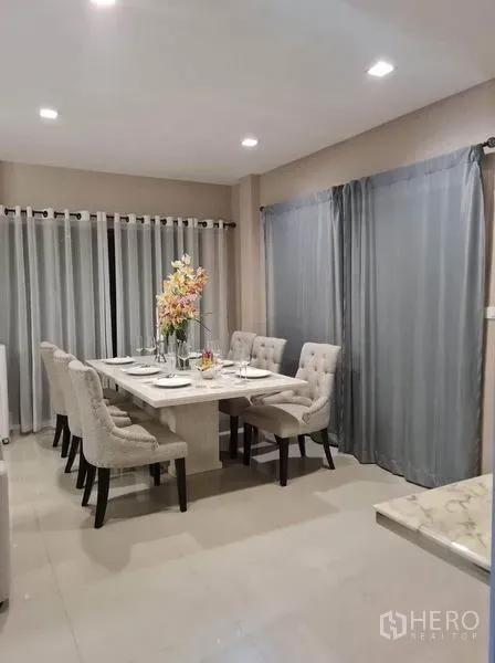 Detached House for rent or sale in Saphan Sung, Bangkok - Bright dining area with six upholstered chairs beside full-height curtains.