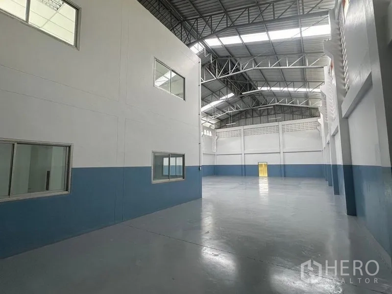 Factory for rent in Pathum Thani - Spacious warehouse hall with high steel truss roof and skylights.