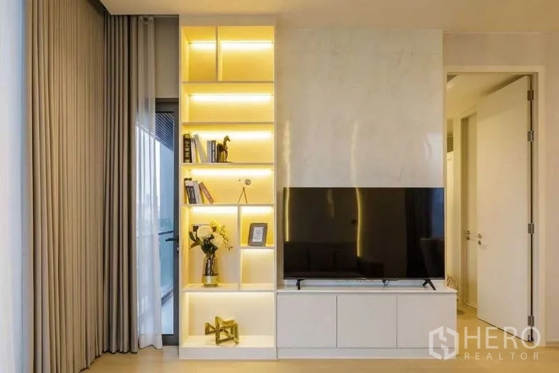 คอนโด ให้เช่าในWatthana, Bangkok - ผนังทีวีพร้อมชั้นโชว์ไฟ LED และประตูออกระเบียงข้างผ้าม่านเต็มสูง