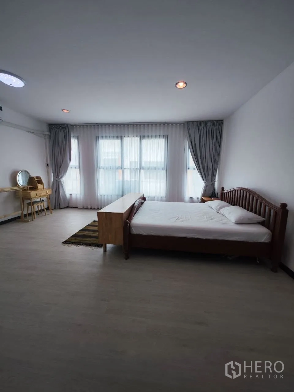 Home Office for rent in Bang Na, Bangkok - Large bedroom with bed, desk and wide windows with curtains.