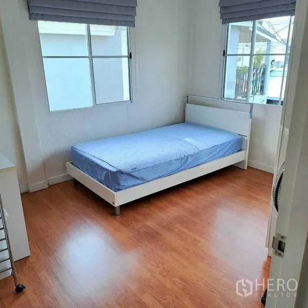 独立式住宅 出租在Prawet, Bangkok - 采光明亮的卧室，单人床，木纹地板，两扇带百叶的窗户。