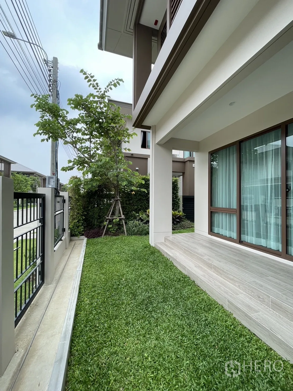 Detached House for rent in Bang Kapi, Bangkok - Side garden with grass lawn along the fence and patio steps.