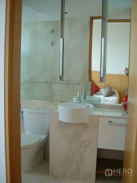 Condominium for rent in Sathon, Bangkok - Modern bathroom with vessel sink, large mirror, glass shower screen, and marble-style tiles.