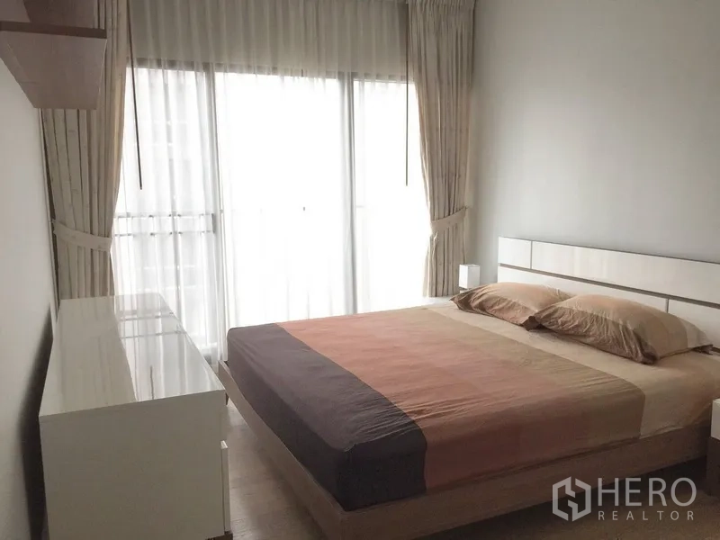 公寓 出租在Bangkok - 主卧配大床、白色斗柜与全落地窗帘。