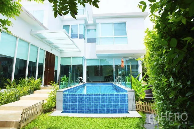 Detached House for rent in Lat Phrao, Bangkok - Garden view of the raised blue‑tiled private pool and landscaped hedges at the contemporary house.