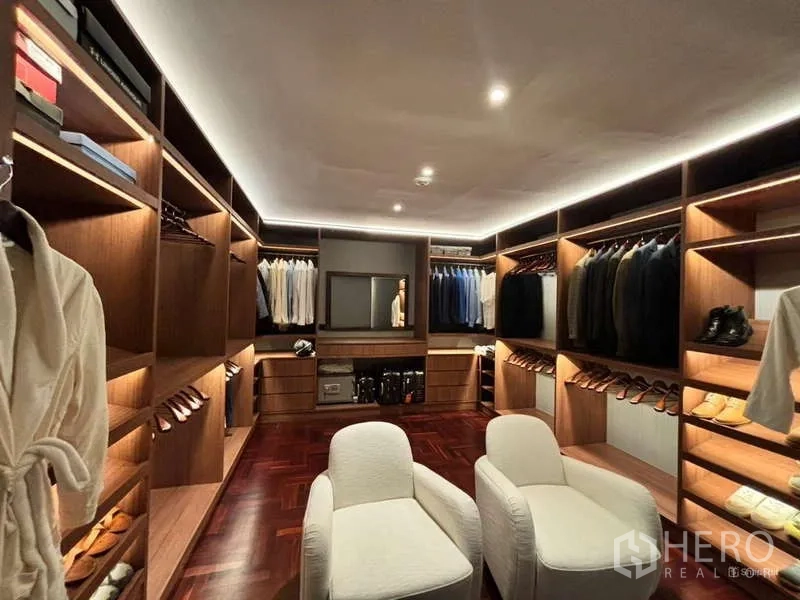 Condominium for rent in Watthana, Bangkok - Custom walk-in wardrobe with extensive wooden shelving and two chairs.