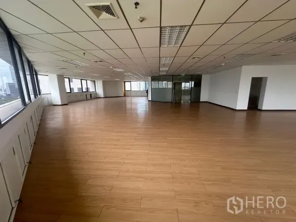 Office Space for rent in Bang Rak, Bangkok - Spacious open-plan office with wood-look floors, drop-ceiling lighting and city-view windows.