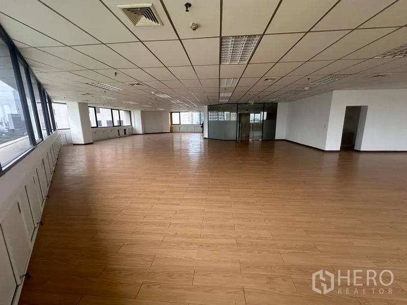 Office Space for rent in Bang Rak, Bangkok - Spacious open-plan office with wood-look floors, drop-ceiling lighting and city-view windows.