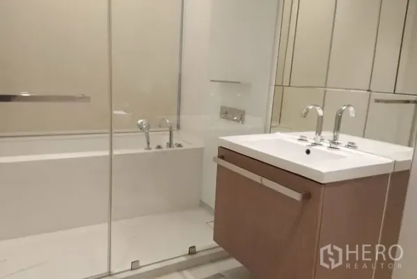 公寓 出租在Pathum Wan, Bangkok - 当代风格浴室，玻璃隔断浴缸、悬空洗手台与宽幅镜面。